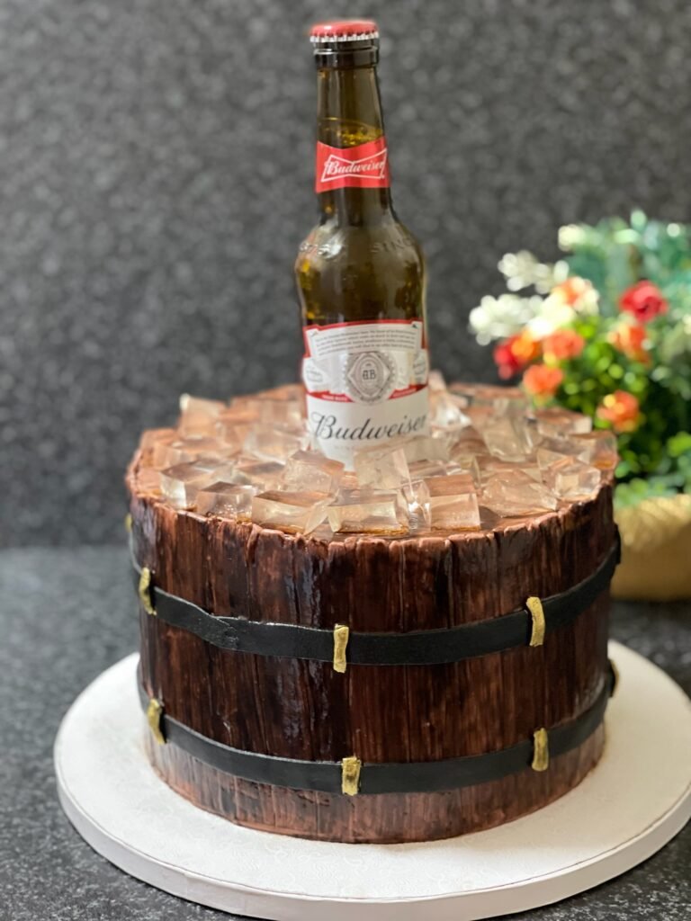 Pastel personalizado con forma de barril de cerveza y botella decorativa en la parte superior, ideal para celebraciones de adultos.